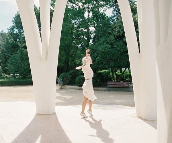 Woman performing a calm, flowing movement in a sunlit, minimalist room.